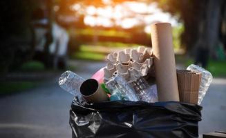 Houseowner is separiting bottles, paper, egg cartons and other stuffs in the black plastic bag in front of the house, concept for reducing global warming, saving our world, soft and selective focus. photo