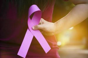 Pink paper ribbon holding in hands of female teenager to show and to call out all people around the world to support and to attend the breast cancer campaign of woman, soft and selective focus. photo