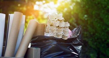 Houseowner is separiting bottles, paper, egg cartons and other stuffs in the black plastic bag in front of the house, concept for reducing global warming, saving our world, soft and selective focus. photo