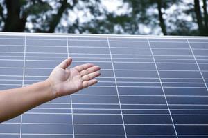 Photovoltaic or solar cell panel behind the left hand showing, soft and selective focus on hand, concept for presenting and showing the photovoltaic panel to store and use the natural power with human photo