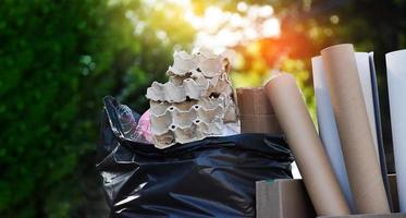 Houseowner is separiting bottles, paper, egg cartons and other stuffs in the black plastic bag in front of the house, concept for reducing global warming, saving our world, soft and selective focus. photo