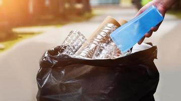 Houseowner is separiting bottles, paper, egg cartons and other stuffs in the black plastic bag in front of the house, concept for reducing global warming, saving our world, soft and selective focus. photo