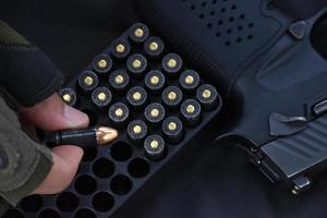 9mm bullet shells holding in fingers and placed near 9mm pistol on black leather background, soft and selective focus on bullet and fingers. photo