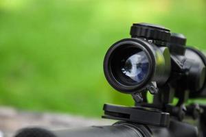 Binoculars of black automatic rifle Long-barreled at the training ground, also known as Air Soft or BB Gun. Use bullets made with spherical plastic beads. Soft and selective focus on binoculars. photo