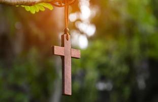 Wooden cross hanging on tree branch, soft and selective focus, natural bokeh tree background, concept for hope, love, forgiveness and belief in Jesus around the world. photo