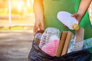 Houseowner is separiting bottles, paper, egg cartons and other stuffs in the black plastic bag in front of the house, concept for reducing global warming, saving our world, soft and selective focus. photo