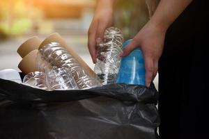 Houseowner is separiting bottles, paper, egg cartons and other stuffs in the black plastic bag in front of the house, concept for reducing global warming, saving our world, soft and selective focus. photo