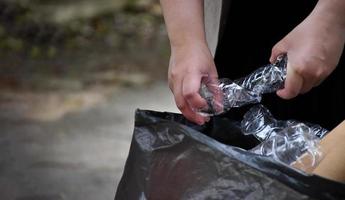 Houseowner is separiting bottles, paper, egg cartons and other stuffs in the black plastic bag in front of the house, concept for reducing global warming, saving our world, soft and selective focus. photo