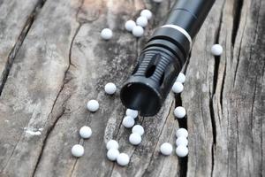 Closeup of white plastic bullets of airsoft gun or bb gun on wooden floor, soft and selective focus on white bullets. photo