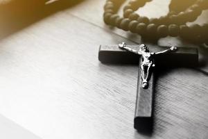 Closeup wooden cross which has a metal statue of crucified Jesus is on wooden table in a local church, soft and selective focus. photo