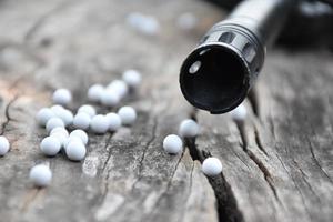 Closeup of white plastic bullets of airsoft gun or bb gun on wooden floor, soft and selective focus on white bullets. photo