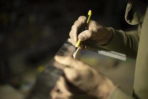 Guy is holding line and pencil. Man marks board. Carpenter measures size of tree. Details of work. photo