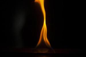 Flames in dark. One flame on black background. Ignition details. Fire burns yellow. photo