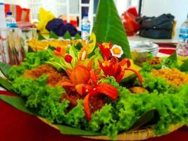 Nasi Tumpeng, yellow rice that is shaped into a cone and equipped with side dishes and vegetables around it. photo