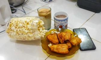 A package of snacks provided to accompany your afternoon, consisting of iced coffee, fried bananas and popcorn. photo