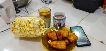 A package of snacks provided to accompany your afternoon, consisting of iced coffee, fried bananas and popcorn. photo