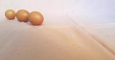 This is a photo of three eggs next to each other on a pink background.