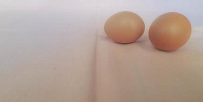 This is a photo of three eggs next to each other on a pink background.