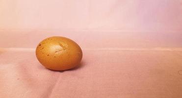 This is photo of a cracked egg, on a pink background.