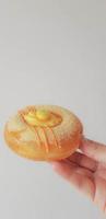 una mano sostiene un donut con un sabor único. en forma de donut en general con un topping de caramelo de naranja y copos de caramelo de naranja. foto