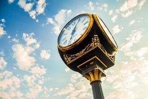 Batumi, Georgia, 2022 - Batumi, Adjara, Georgia. Old golden vintage clock with greek numbers, sunflare, building and blue sky in the background. Old town in Georgia photo