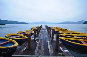 botes de remos y embarcadero de madera por la mañana en un lago tranquilo foto