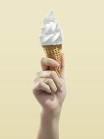 Ice cream cone on yellow background, woman holding ice cream by hand photo