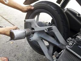 Close up of a motorcycle mechanic using an air gun to loosen the wheel nuts in a mechanical workshop photo