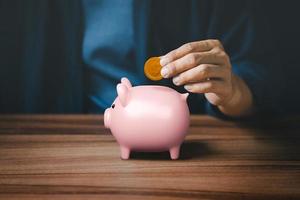 Man putting coin into piggy bank for saving money concept, business finance and investment. photo