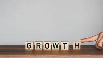 Man's hand scrolling the letter H to combine with the rest of the words to get the word growth on wooden cubes block. photo