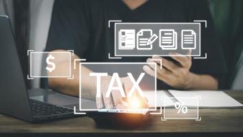 Financial tax return concept, a man's hand using a smartphone and a computer to work in accounting and tax photo