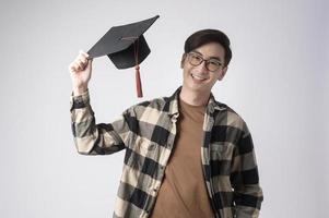 joven sonriente sosteniendo sombrero de graduación, educación y concepto universitario foto