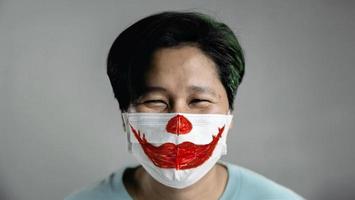 halloween en concepto de situación covid-19. persona feliz con una máscara quirúrgica. lápiz labial rojo sonriente pintado en la máscara foto