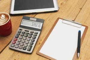 The top view of the office desk blank paper, pen, calculator, tablet. Financial planning and work concept. photo