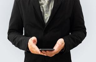 Front view of a businessman in a black suit who uses both hands holding a smartphone on a white background with a clipping path. photo