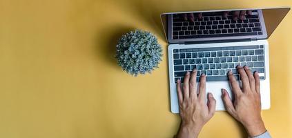 hombre usando computadora portátil con teclado sobre fondo amarillo. copie el espacio foto