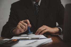 Man stamping approval of work finance banking or investment marketing documents on desk. photo