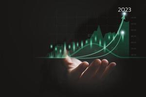 hombre de negocios que sostiene la flecha del gráfico de datos de crecimiento con el diagrama de presupuesto de 2023, gráfico de negocios estrategia de motivación y desarrollo de éxito futuro corporativo foto