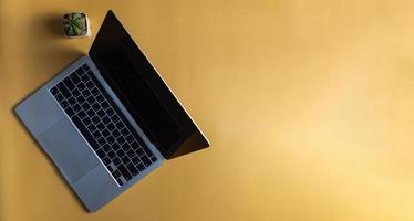 computer laptop and cactus on yellow background.Top view copy space blank. photo