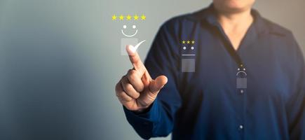 Customer service and Satisfaction concept, Business person are touching the virtual screen on happy Smiley face icon to give satisfaction in service. rating very impressed. customer service feedback. photo