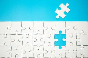 White part of jigsaw puzzle pieces on blue background. concepts of problem solving, business success, teamwork, Team playing jigsaw game incomplete, Texture photo with copy space for text