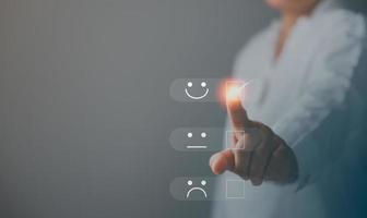 servicio al cliente y concepto de satisfacción, la persona de negocios está tocando la pantalla virtual en el icono de la cara sonriente feliz para dar satisfacción en el servicio. calificación muy impresionado. retroalimentación del servicio al cliente. foto