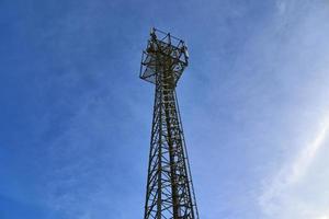 Electric antenna and communication transmitter tower in a northern european landscape against a blue sky photo