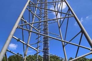 Electric antenna and communication transmitter tower in a northern european landscape against a blue sky photo