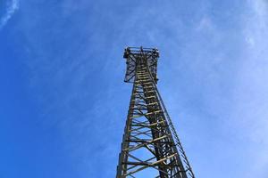 Antena eléctrica y torre transmisora de comunicaciones en un paisaje del norte de Europa contra un cielo azul foto