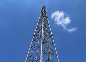 Antena eléctrica y torre transmisora de comunicaciones en un paisaje del norte de Europa contra un cielo azul foto