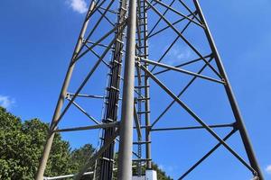 Electric antenna and communication transmitter tower in a northern european landscape against a blue sky photo