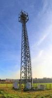 Antena eléctrica y torre transmisora de comunicaciones en un paisaje del norte de Europa contra un cielo azul foto