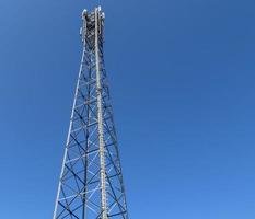 Antena eléctrica y torre transmisora de comunicaciones en un paisaje del norte de Europa contra un cielo azul foto