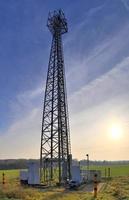 Antena eléctrica y torre transmisora de comunicaciones en un paisaje del norte de Europa contra un cielo azul foto